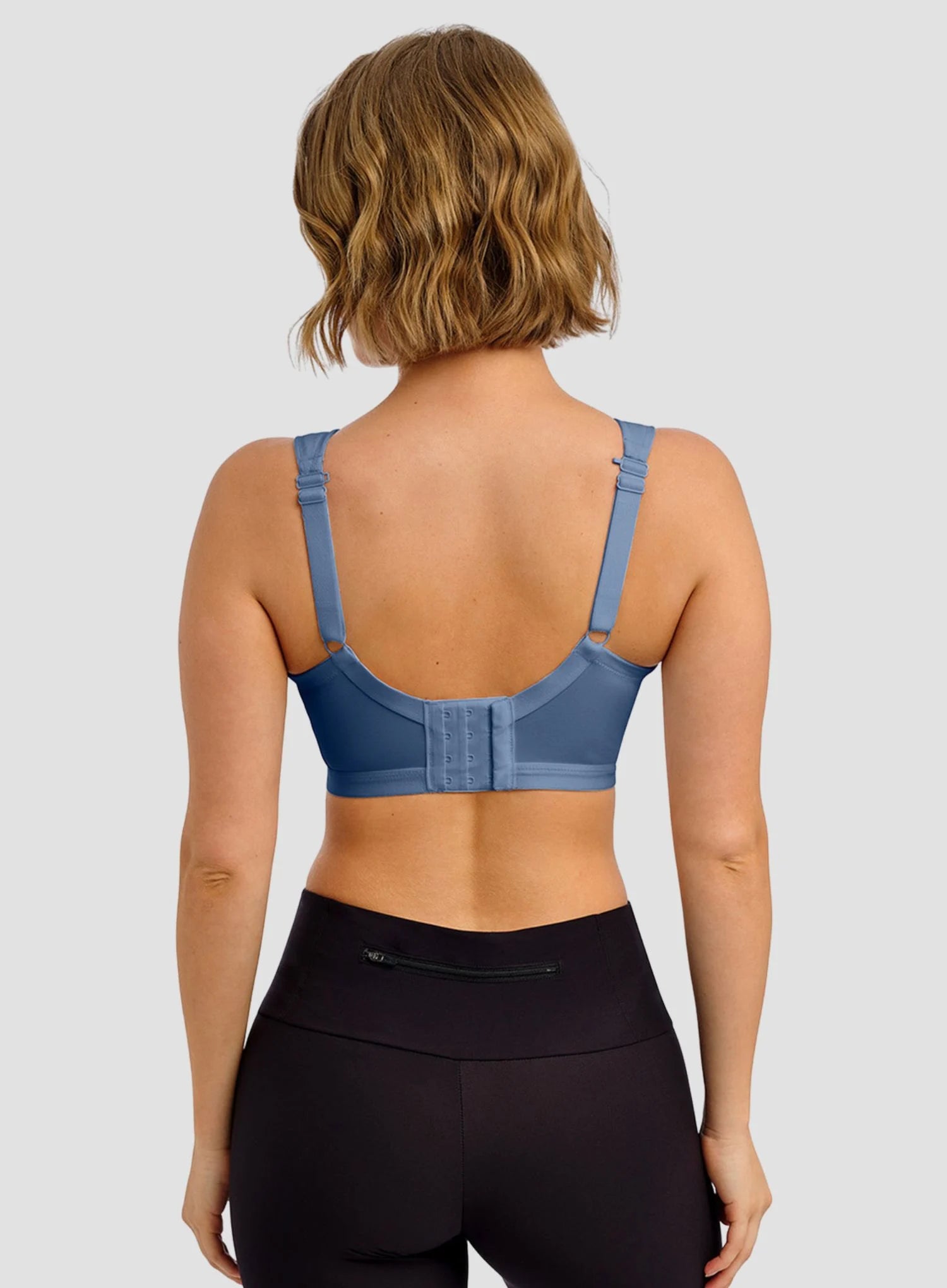 Person wearing a blue sports bra and black leggings on a light gray background