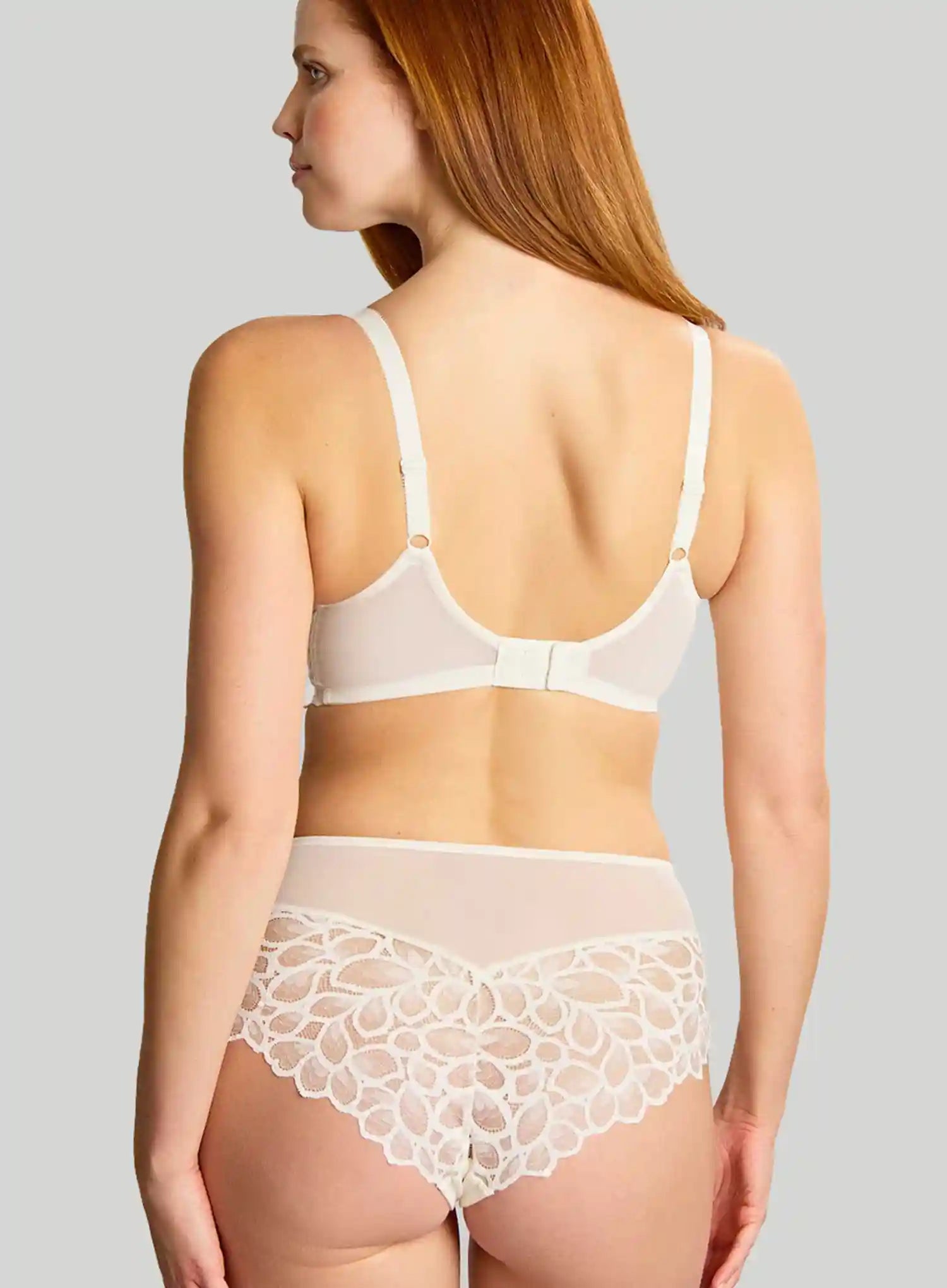 Woman wearing a white bra and lace underwear set on a gray background