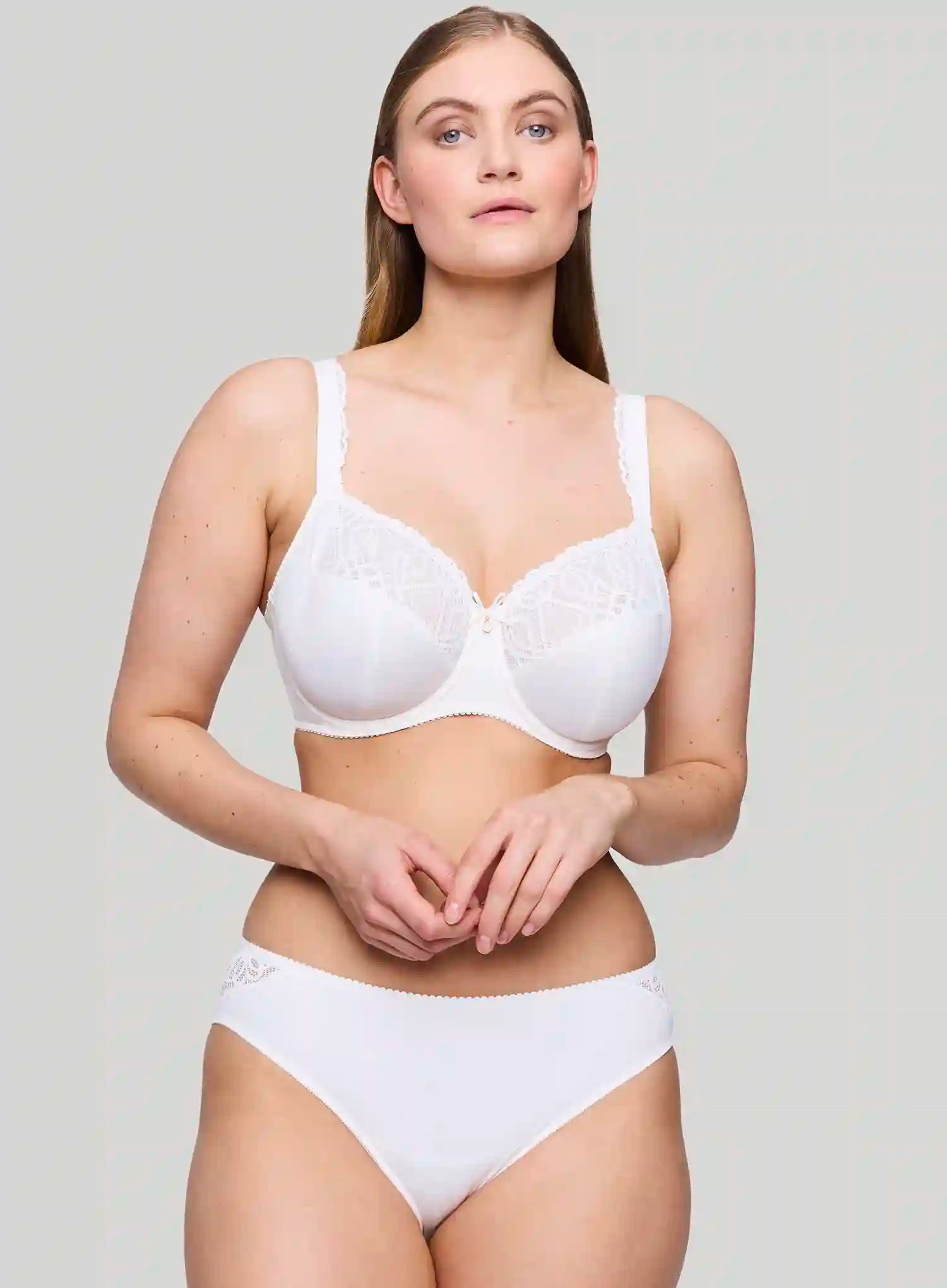 Woman wearing a white bra and panties set against a plain background
