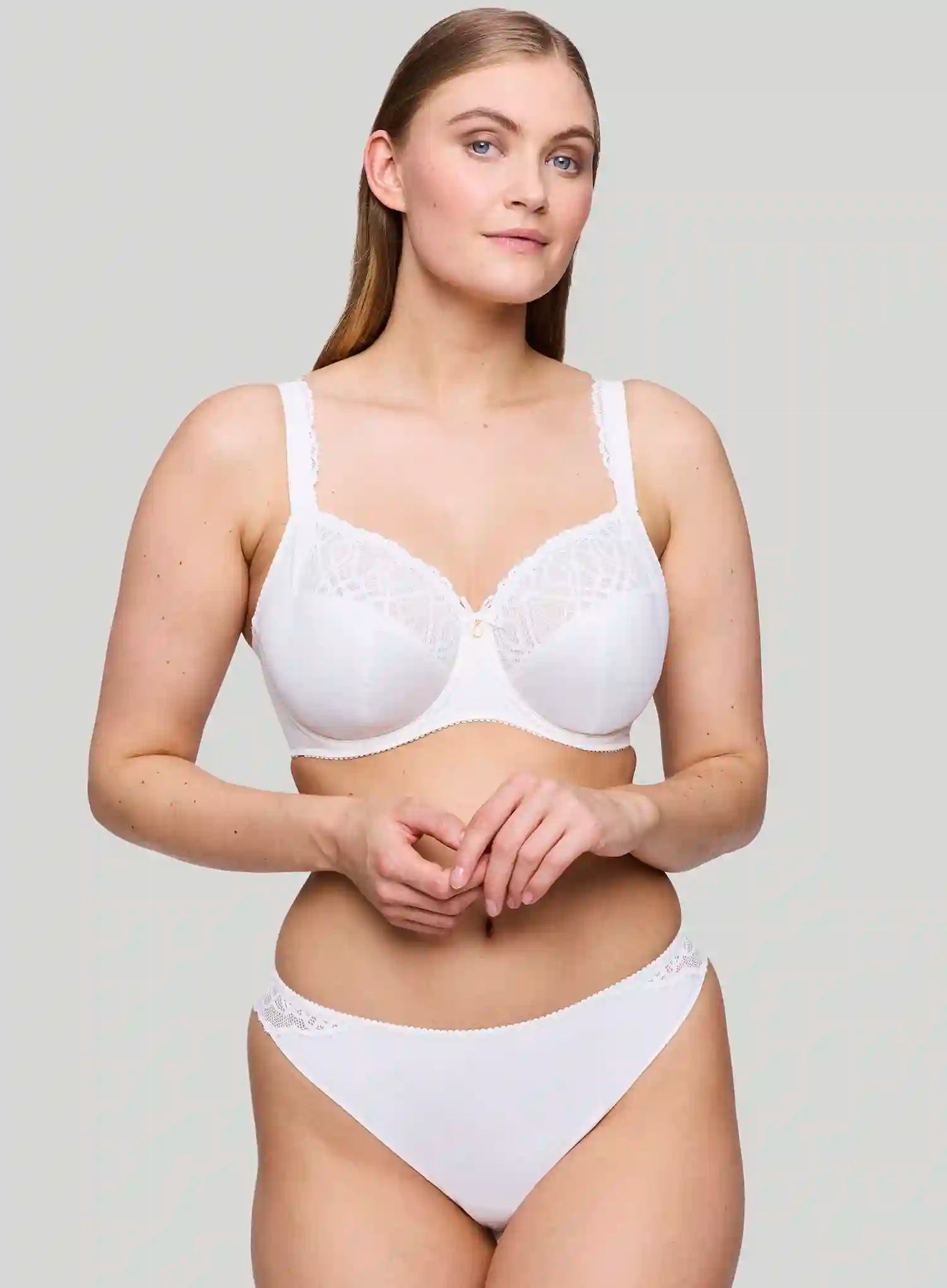 Woman wearing a white bra and underwear set on a plain background