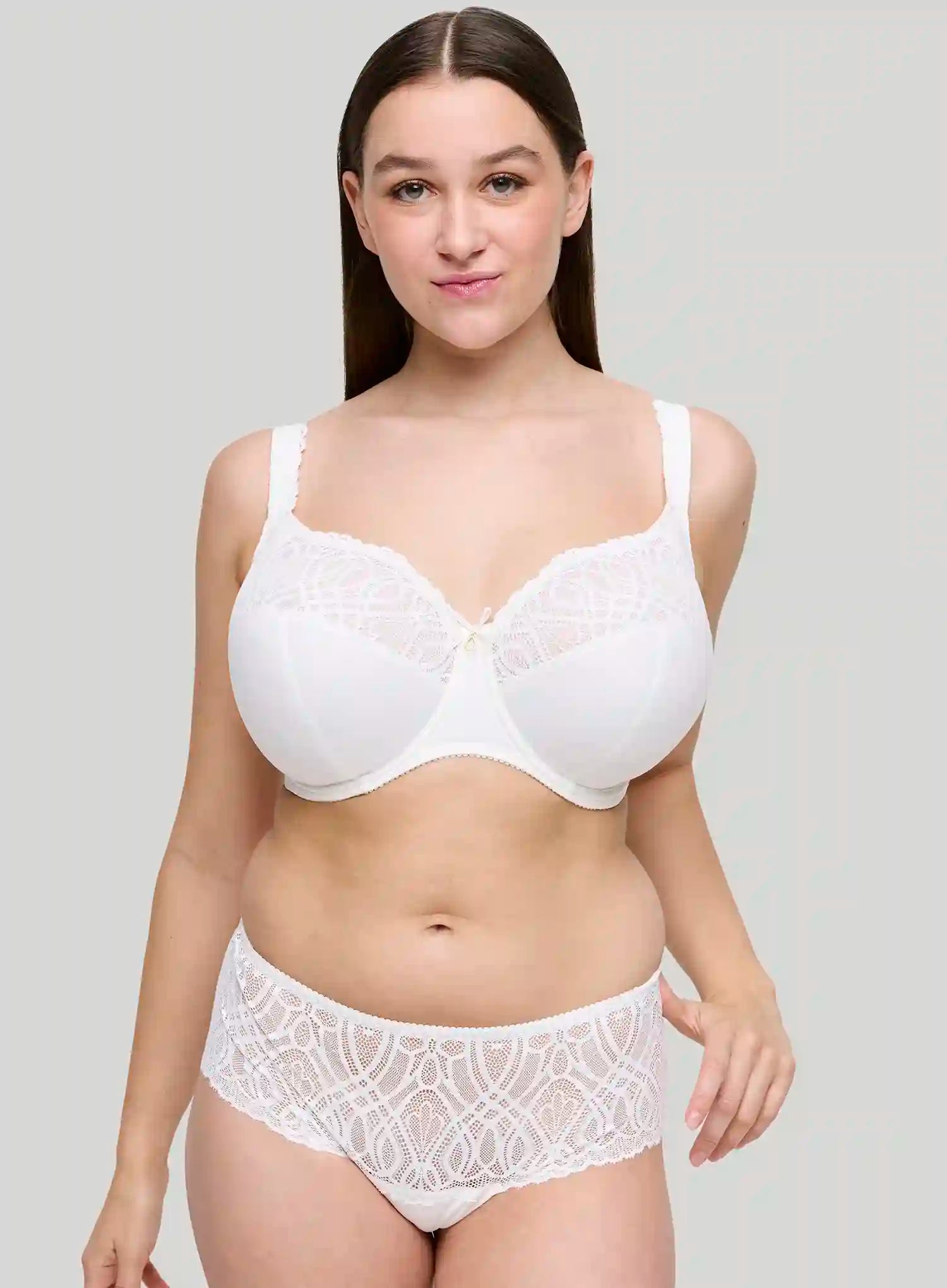 Woman wearing a white bra and panties set against a plain background