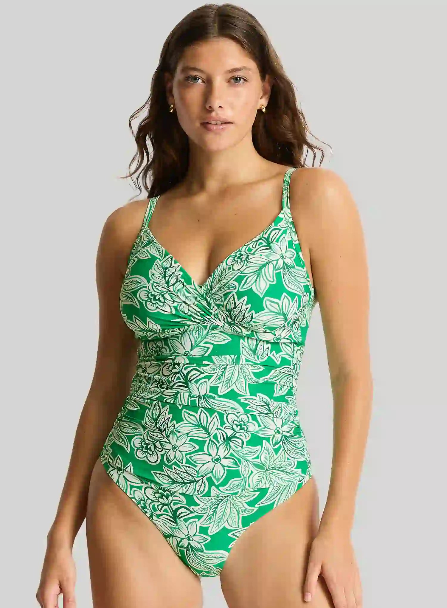 Woman wearing a green and white floral swimsuit on a gray background