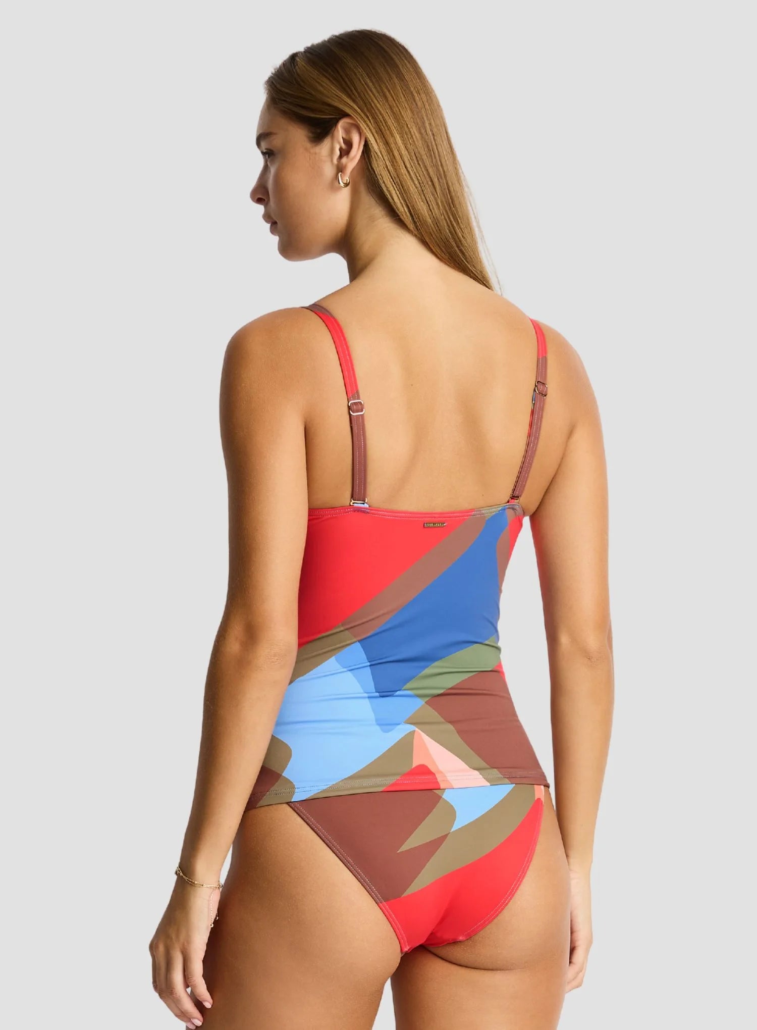 Woman wearing a colorful geometric-patterned swimsuit on a light gray background